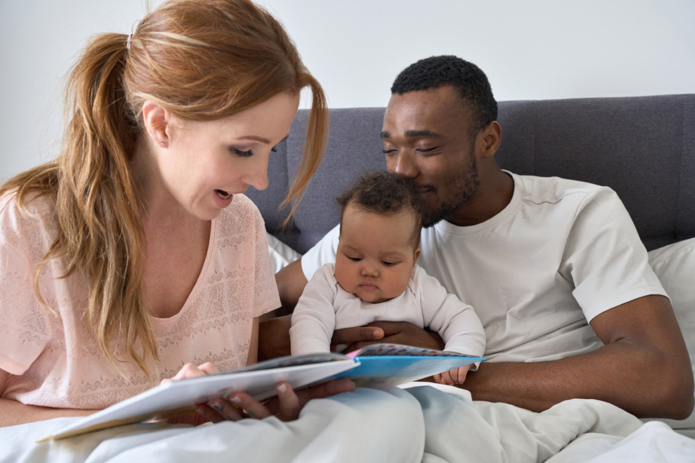 Interracial couple reading to their newborn baby