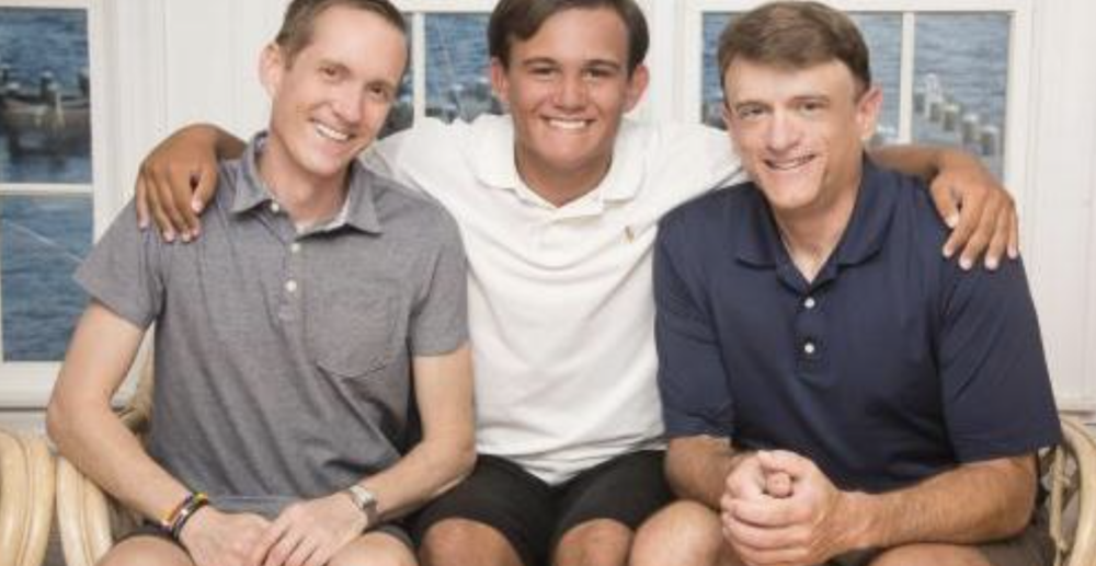 Adoptive Family Smiles with Son Putting Arms Around His Dads