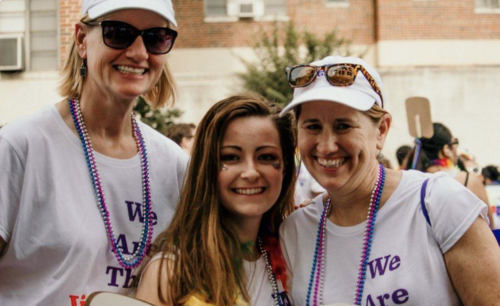 Young girl smiling at a Pride celebration with her moms