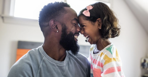 Child and father smiling and placing their foreheads together
