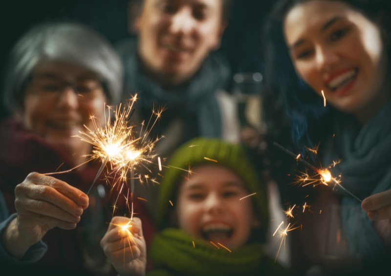 Family lights sparklers together on new years eve