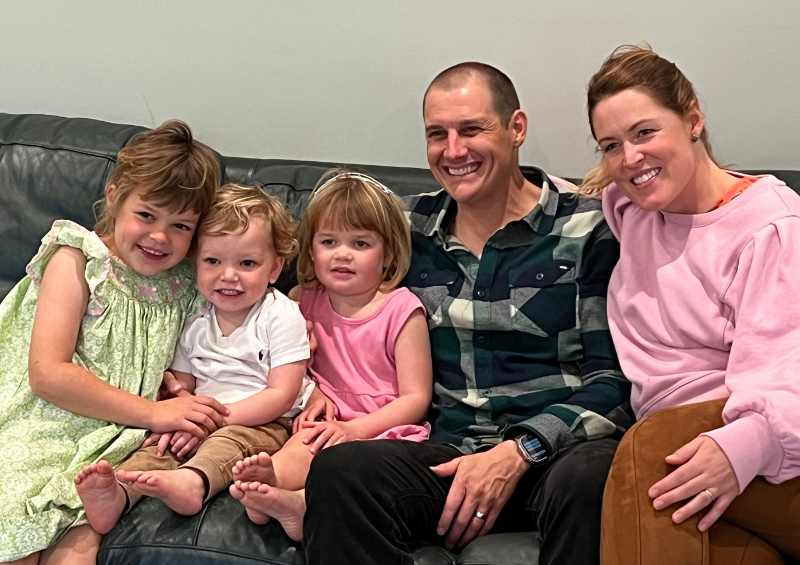The Caldwell Family smiles for a photo while sitting on a couch