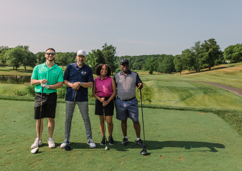 A foursome of golfers smiling at the camera at a golf tournament fundraiser