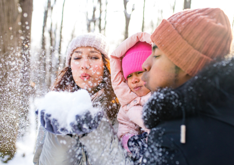 Family playing in the snow and blowing snow