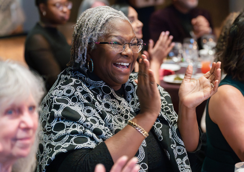 A woman at the gala claps and smiles
