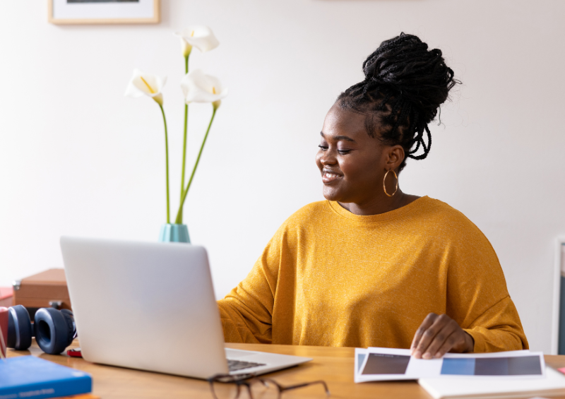 A woman sits at her desk and smiles at her computer