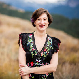 A woman smiles in front of a scenic background