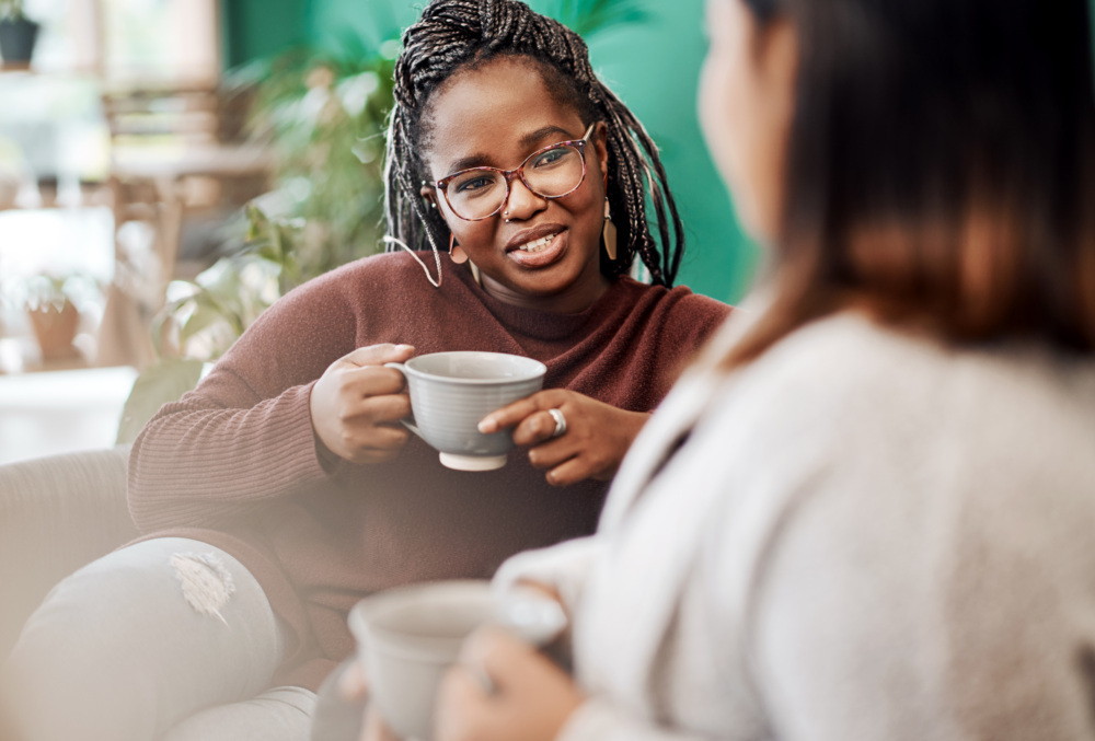 Two women sit and enjoy coffee together in a comfortable setting