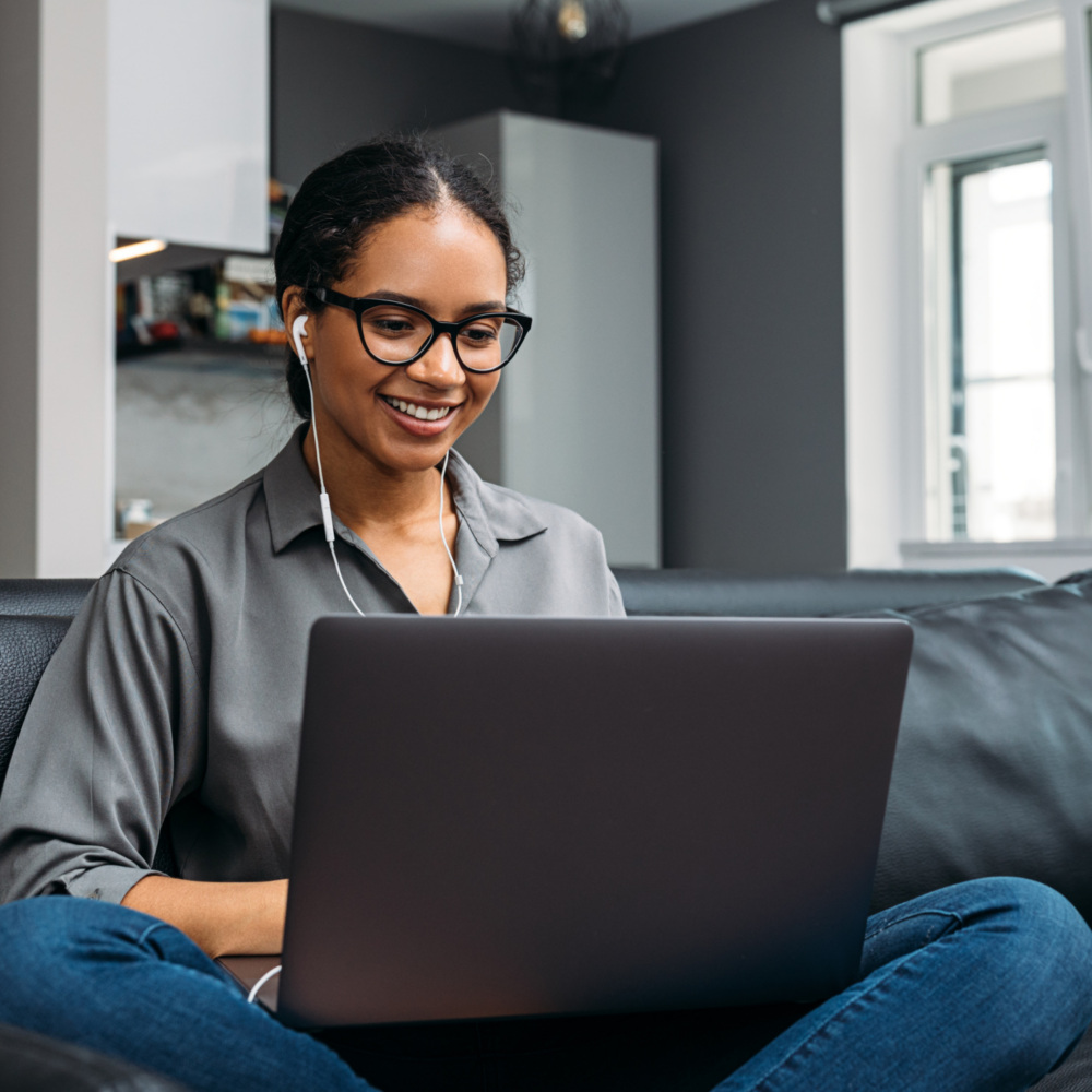 Young woman video calling using a laptop sitting on a sofa