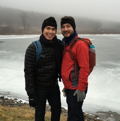 Two men smile in front of a frozen lake